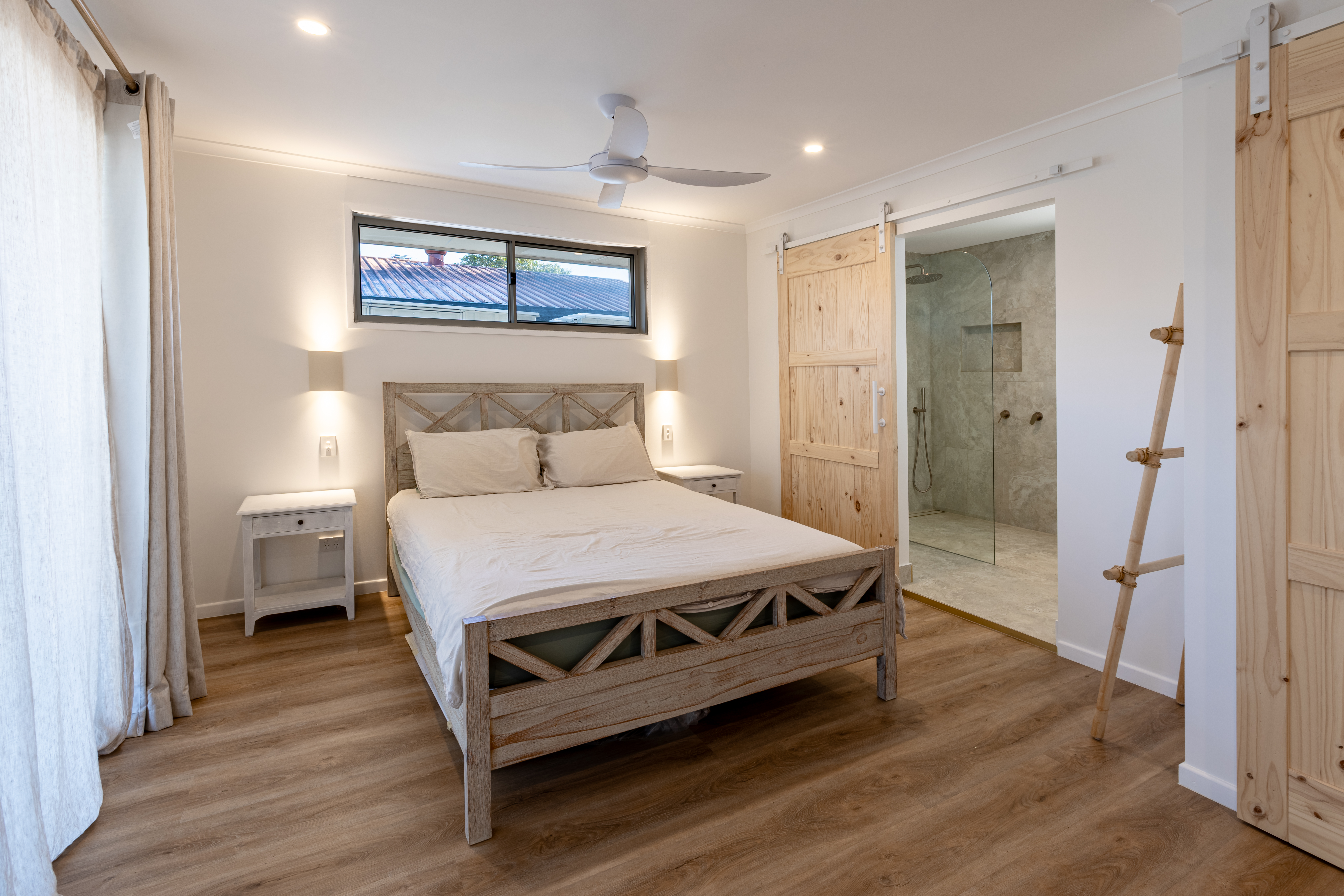 Bedroom with wall sconces and ceiling fan — Sunrise Beach renovation