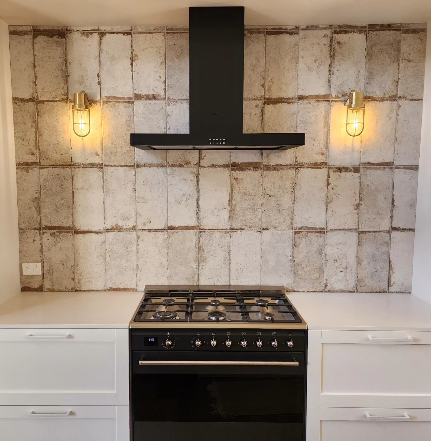 Brass cage wall lights flanking a kitchen range hood