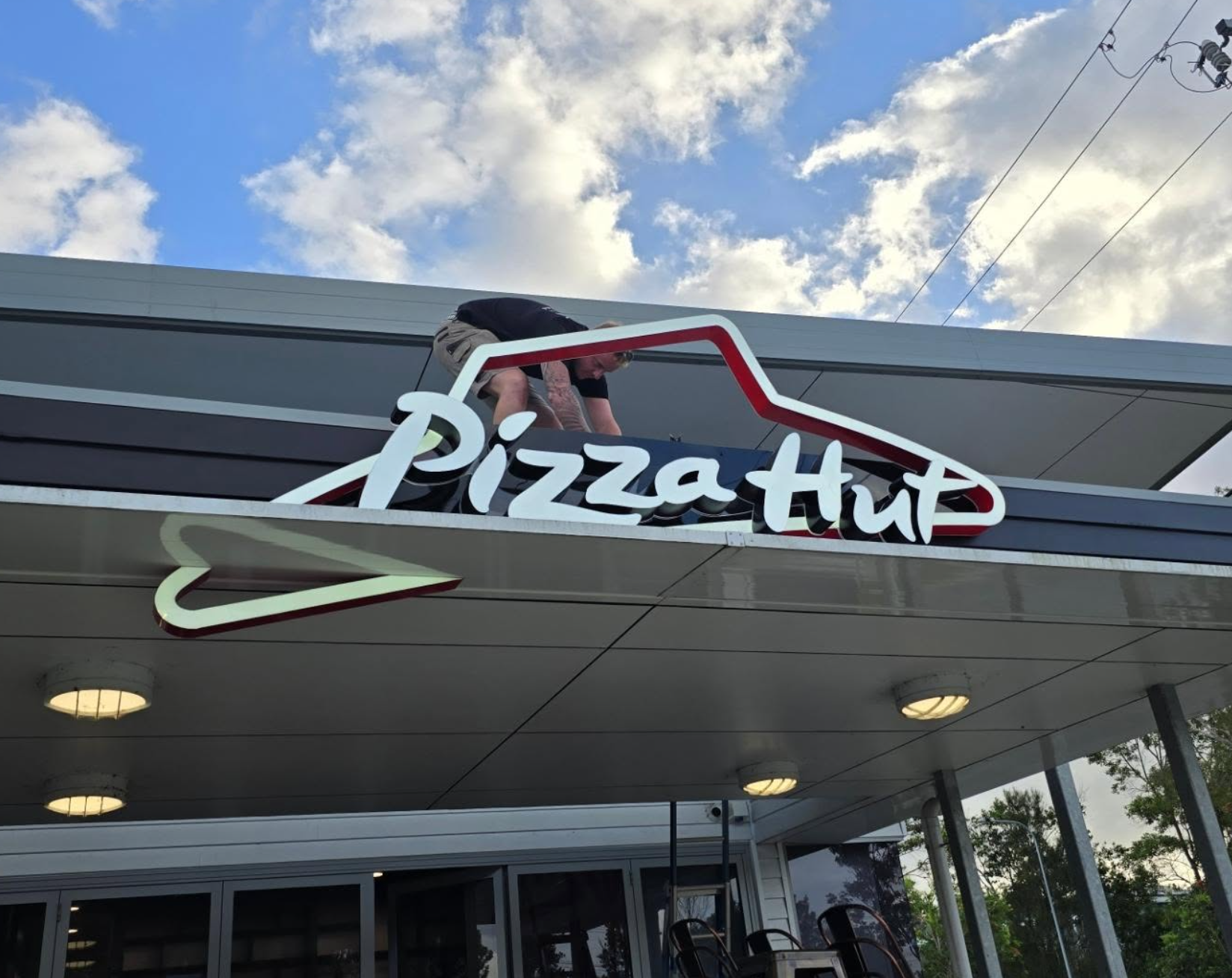 Wave Electrical technician installing Pizza Hut illuminated signage on the rooftop
