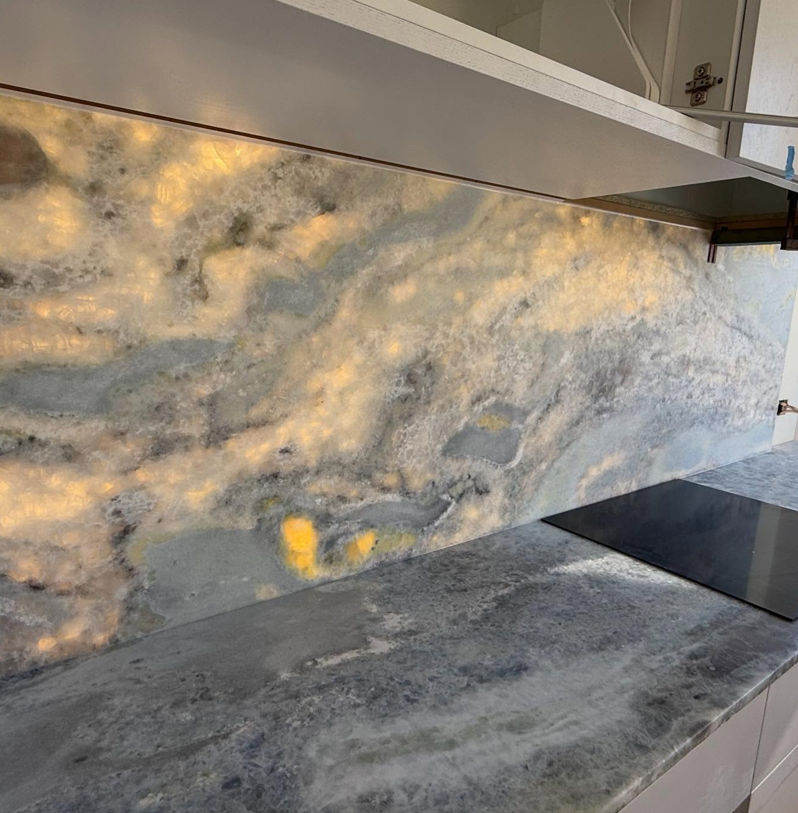 Close-up of LED backlit onyx stone splashback with induction cooktop — Noosa