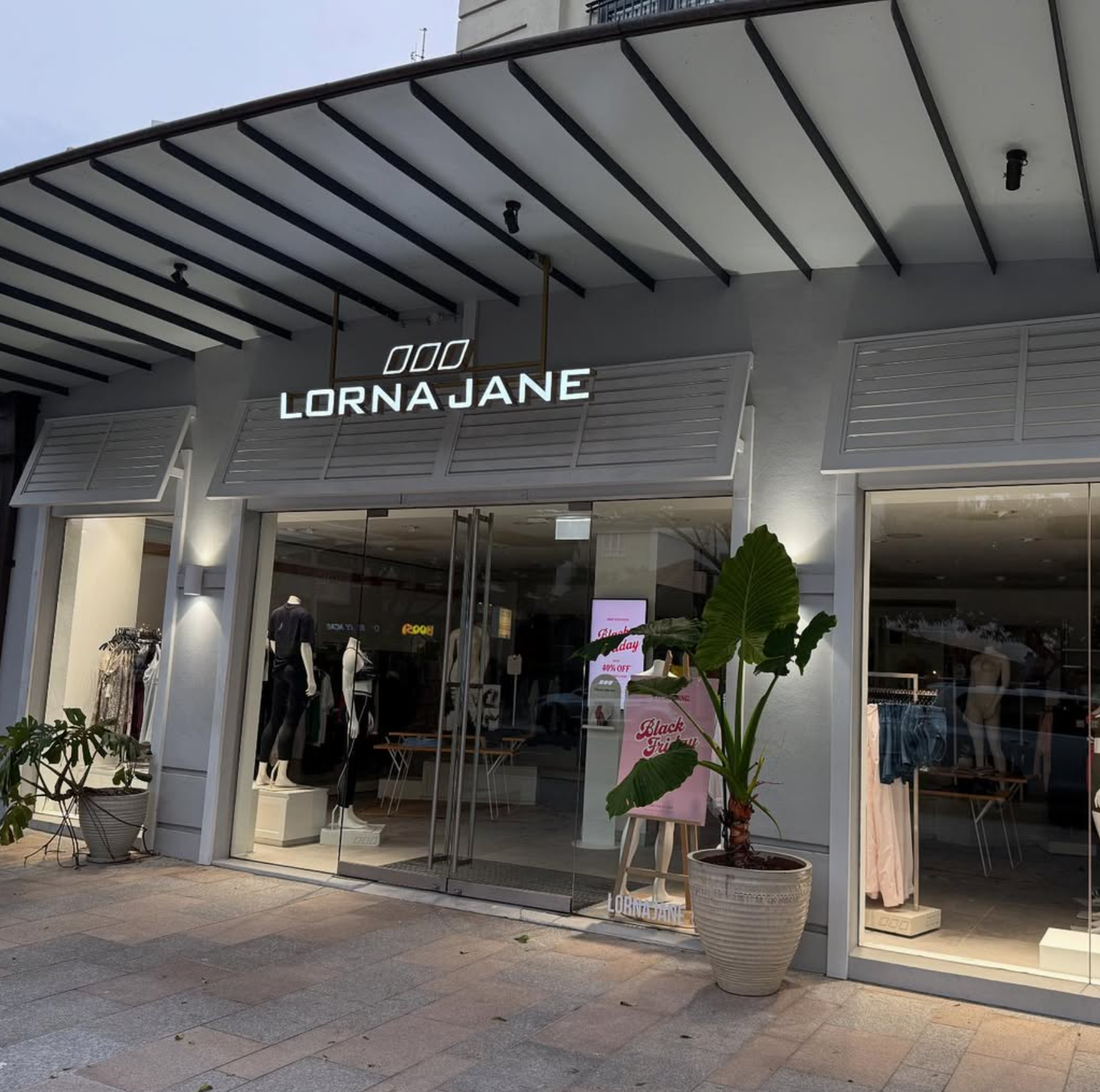 Lorna Jane storefront lit up at dusk with wall lights and downlights — Noosa commercial fit-out