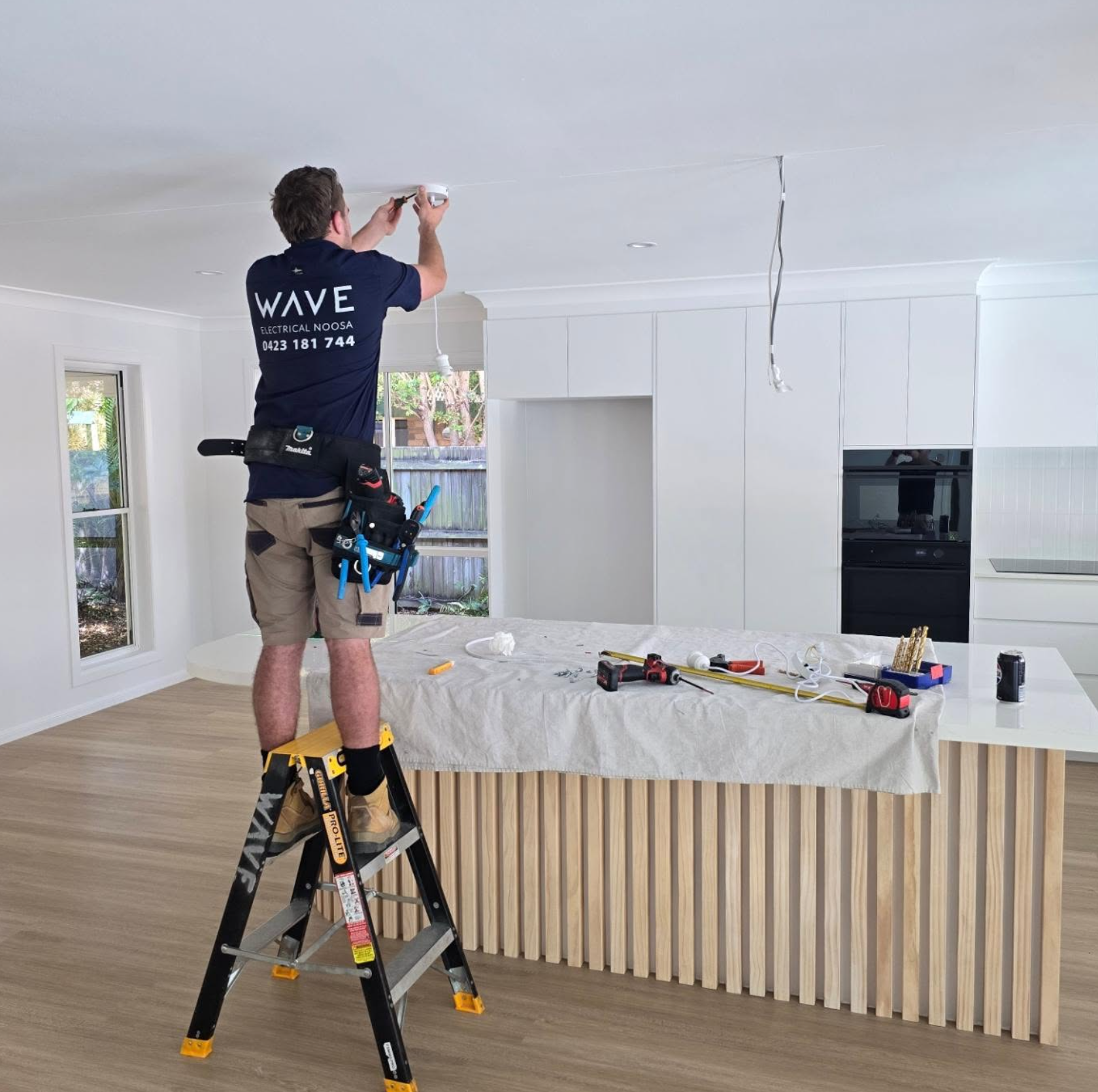 Wave Electrical technician installing lighting in a brand new open-plan kitchen — new build Noosa